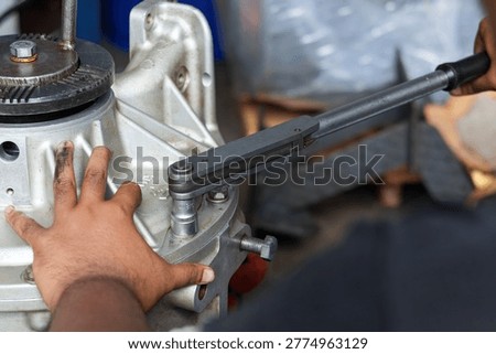 A professional technician uses a precision torque wrench to tighten bolts on a heavy-duty aluminum transmission casing during a mechanical assembly process.