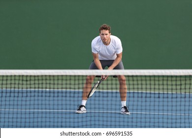 Professional tennis player man athlete waiting to receive ball, playing game on hard court. Fitness person focused behind net ready to return training cardio on outdoor sport activity. - Powered by Shutterstock