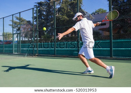 Professional tennis player playing a game of tennis on a court. He is about to hit the ball with the racket. The ball is suspended in the air. 