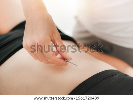Professional therapist centre examining the body reflexion. The doctor checks the patient reflex with special needle tool.