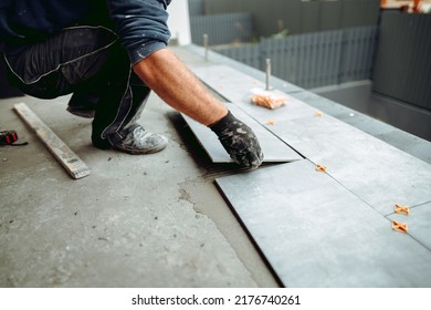 Professional tiler and ceramic tiles worker on construction site. hands of the tiler are laying the ceramic tile on the floor.