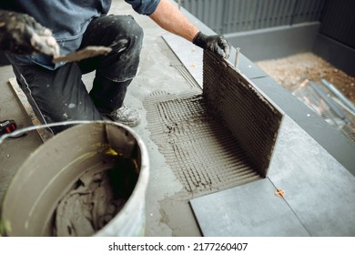 Professional tiler and ceramic tiles worker on construction site. hands of the tiler are laying the ceramic tile on the floor.