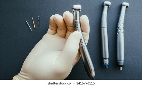 Professional tools. Hand of dentist in latex protective gloves holding dental drill handpiece.