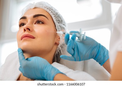 Professional Treatment. Positive Nice Woman Smiling While Having An Injection In The Cheek