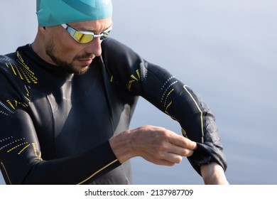 Professional Triathlete Before Swimming In River's Open Water. Man Wearing Swim Equipment Practicing Triathlon On The Beach In Summer's Day. Concept Of Healthy Lifestyle, Sport,