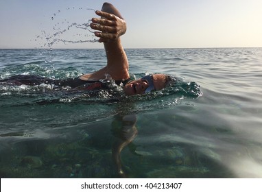 Professional Triathlete Practicing In Open Water. Swimming In Sea. Triathlon Training In Wetsuit.