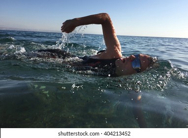 Professional Triathlete Practicing In Open Water. Swimming In Sea. Triathlon Training In Wetsuit.