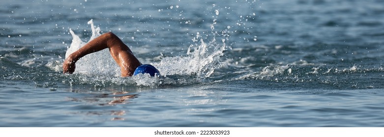 Professional triathlete swimming in ocean open water, male triathlon swimmer swimming in professional triathlon suit training - Powered by Shutterstock