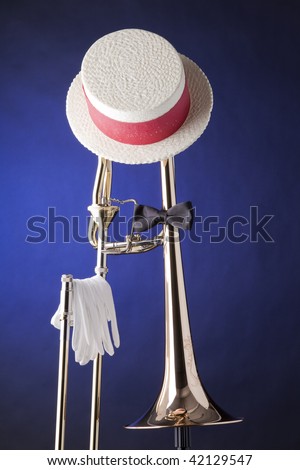 A professional trombone with hat, bow tie, and gloves, isolated against a spotlight blue background.