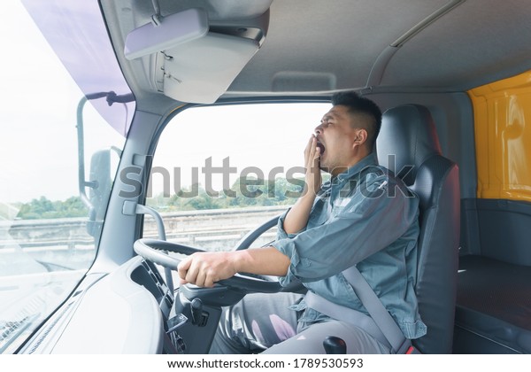 Professional truck driver,\
adult male, safety belt Yawning and sleepy. Young man worker is\
confident in the safety of the transport and delivery business for\
a long time.