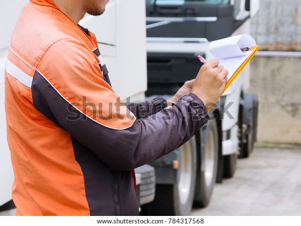Professional truck driver checks list a truck on clip
board 