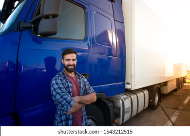 Professional truck driver with crossed arms standing by his semi truck. Trucker occupation and transportation services.