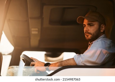 Professional Truck Driver Driving In Reverse While Looking In Side View Mirror.