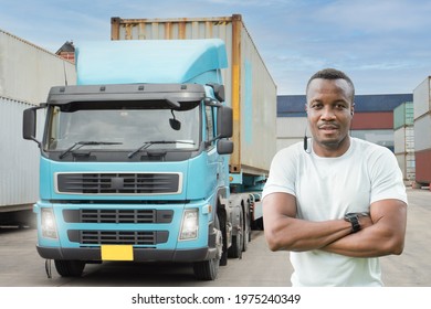 Professional Truck Driver Standing Arm Folded Smiling In Front Of The Semi Truck Container Yard. African Young Man Cheerful Proud Business Owner  Delivery Transportation Carry Import Export Warehouse