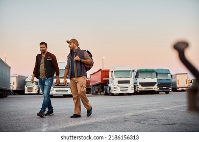 Professional truck drivers talking while walking on parking lot. Copy space.
