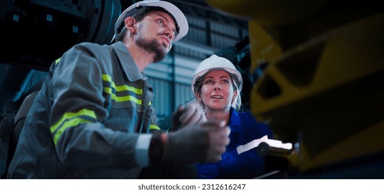 Professional, Two industrial engineer colleague or technician worker wearing safety uniform, hard hat using tablet discuss automated robotic arm machine in factory. Automatic Industry concept. - Powered by Shutterstock