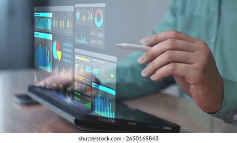 Professional using a stylus pen to control a digital dashboard displayed as a holographic interface from a laptop. The screen showcases data analysis, performance charts, and smart infographics. 