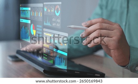 Professional using a stylus pen to control a digital dashboard displayed as a holographic interface from a laptop. The screen showcases data analysis, performance charts, and smart infographics. 