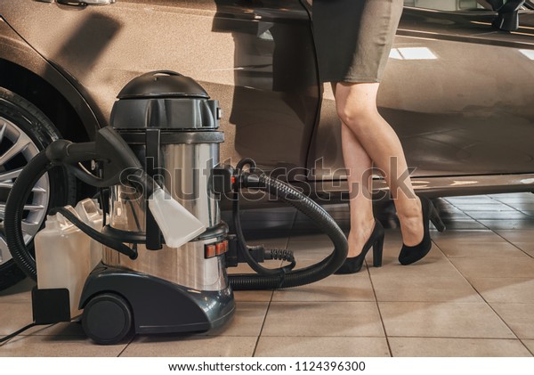 Professional vacuum cleaner for\
chemist car in the car service and a fragment of elegant female\
legs