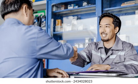 Professional vehicle maintenance man holding clipboard and talk with asian man customer at car service garage. Car repair and customer service concept, Discussing the cost of car repairs at the desk - Powered by Shutterstock