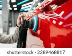 Professional vehicle polishing and detailing service in a modern car workshop. Brightly lit workspace with large led lights. High quality car valeting concept.