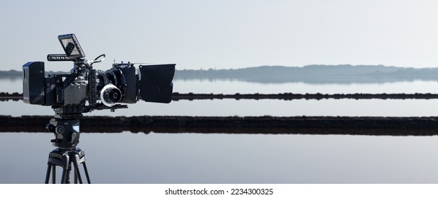 Professional video camera with lake landscape background. Documentary film or movie production banner with copy space. - Shutterstock ID 2234300325