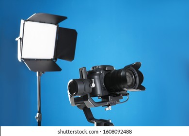 Professional Video Camera And Lighting Equipment On Blue Background