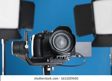 Professional Video Camera And Lighting Equipment On Blue Background