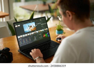 Professional video colorist adjusts footage colors on laptop in bright office. Creative industry editor works on film grading, enhances visual appeal. Expert uses software for post-production. - Powered by Shutterstock