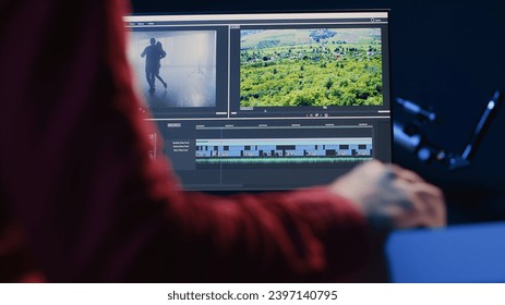 Professional video editor editing color grading and lighting in creative office, analyzing film montage, close up shot. Post production videographer manipulates raw footage, handheld camera shot