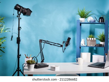 Professional video light stand in empty vlog broadcasting studio with microphone used for recording social media content. Vlogging setup with digital mixer console and laptop computer.