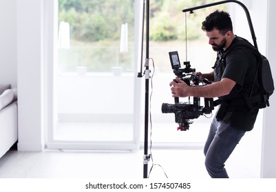 Professional videographer with gimball video slr recording video on professional camera at home