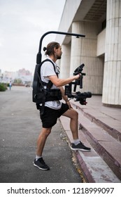 Professioneller Videograf, der eine Kamera auf 3-achsigem Gimbal hält, die auf einfachem Rigg montiert ist. Videograf mit Steadicam. Pro-Ausrüstung hilft, qualitativ hochwertiges Video ohne Schütteln zu machen.