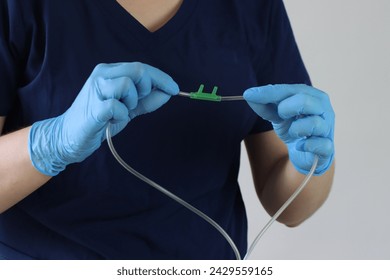 Professional wearing gloves holding a nasal cannula for oxygen delivery. Professional simulating holding the cannula to put in a patients face - Powered by Shutterstock