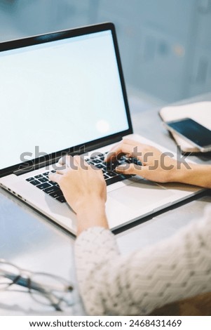 Professional web designer using application on netbook with mock up screen for  creating project, back view of female manager making online research browsing web page on laptop computer in office
