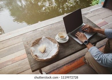 Professional web designer using laptop with mock up screen for creating project. Top view of designer making  web page on laptop computer in co-working space near pond.