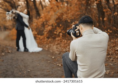 Professional wedding photographer in action. the bride and groom in nature in autumn - Powered by Shutterstock