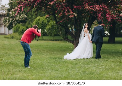 Professional wedding photographer in the process of photographing with the newlyweds in nature. Photography, concept. - Powered by Shutterstock