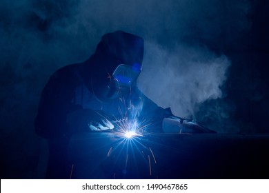 Professional Welder And Mask Welding Metal Pipe On The Industrial Table.A Welder Is A Tradesperson Who Specializes In Fusing Materials Together.