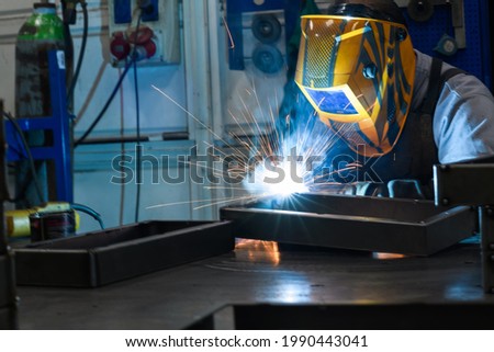 Professional welder performs work with metal parts in factory, sparks and electricity. Industry worker banner.
