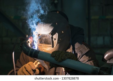 A professional welder welds a pipe with a diameter of DN50 for a process pipeline to an oil refinery in Russia.
