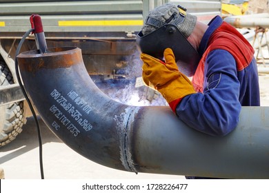 A professional welder works by manual-arc welding with an electrode, and receives a weld of technological pipelines DN 250 for an oil refinery in Russia                  - Powered by Shutterstock