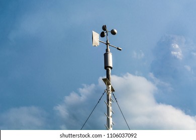 Professional Wind Weather Vane And Cloudy Dramatic Blue Sky In Weather Station. Meteorology Concept.  Automatic Weather Station For Monitoring Ambient Air Pressure, Humidity, Wind Speed And Direct