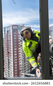 Professional Window Cleaner at Work Overlooking a Modern Cityscape on a Bright Sunny Day in a High-Rise Building, Ensuring Crystal Clear Views for Residents with Safety Gear