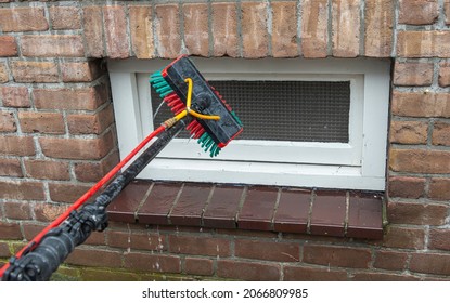 professional window squeegee brush connected to a water hose with an extendable telescopic rod washing a small square window - Shutterstock ID 2066809985