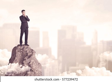 A Professional Winner Business Person Standing On A Dangerous Mountain Top Above The City Scape With Clouds Concept