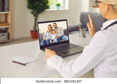 Professional Woman Doctor In Uniform Sitting Backwards And Greeting Young Happy Family With Child During Online Consultation Videocall On Laptop. Telemedicine, Online Medicare Concept