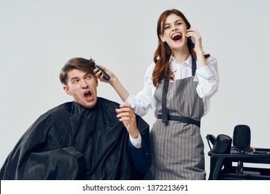 Professional Woman Hairdresser Talking On The Phone And Doing A Haircut To A Man