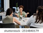 A professional woman leads a vibrant conversation among colleagues in a stylish workplace.