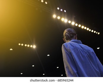 Professional Woman Model On Ramp Stage With Full Scale Lighting On Ceiling, Shoot From Behind No Face, Low Exposure